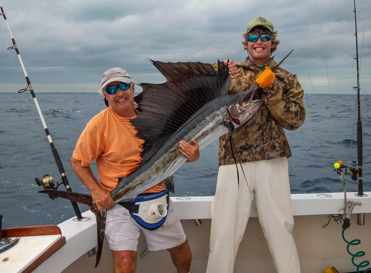 An Angler about the Restless Too chater boat holding a sailfish caught from while anchored